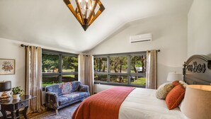 A bedroom with a bed, a sofa, a desk, and a window with a view of trees. - Beautiful Log Farmhouse in Paradise Valley, Montana (Livingston)