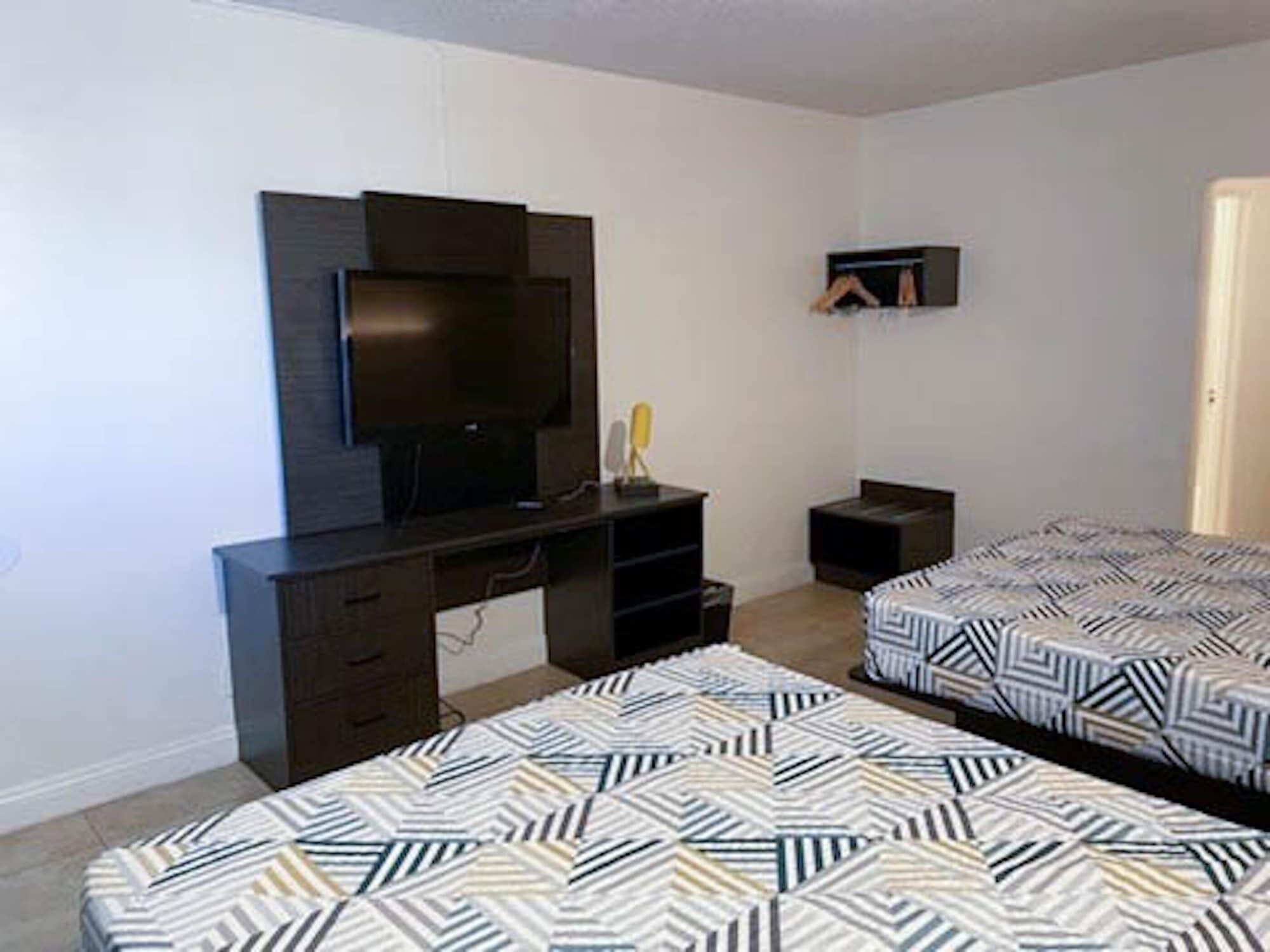 A bedroom with two beds, a TV, a desk, and a wardrobe.