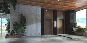Un vestíbulo moderno con pared de concreto, un ascensor y plantas en macetas.