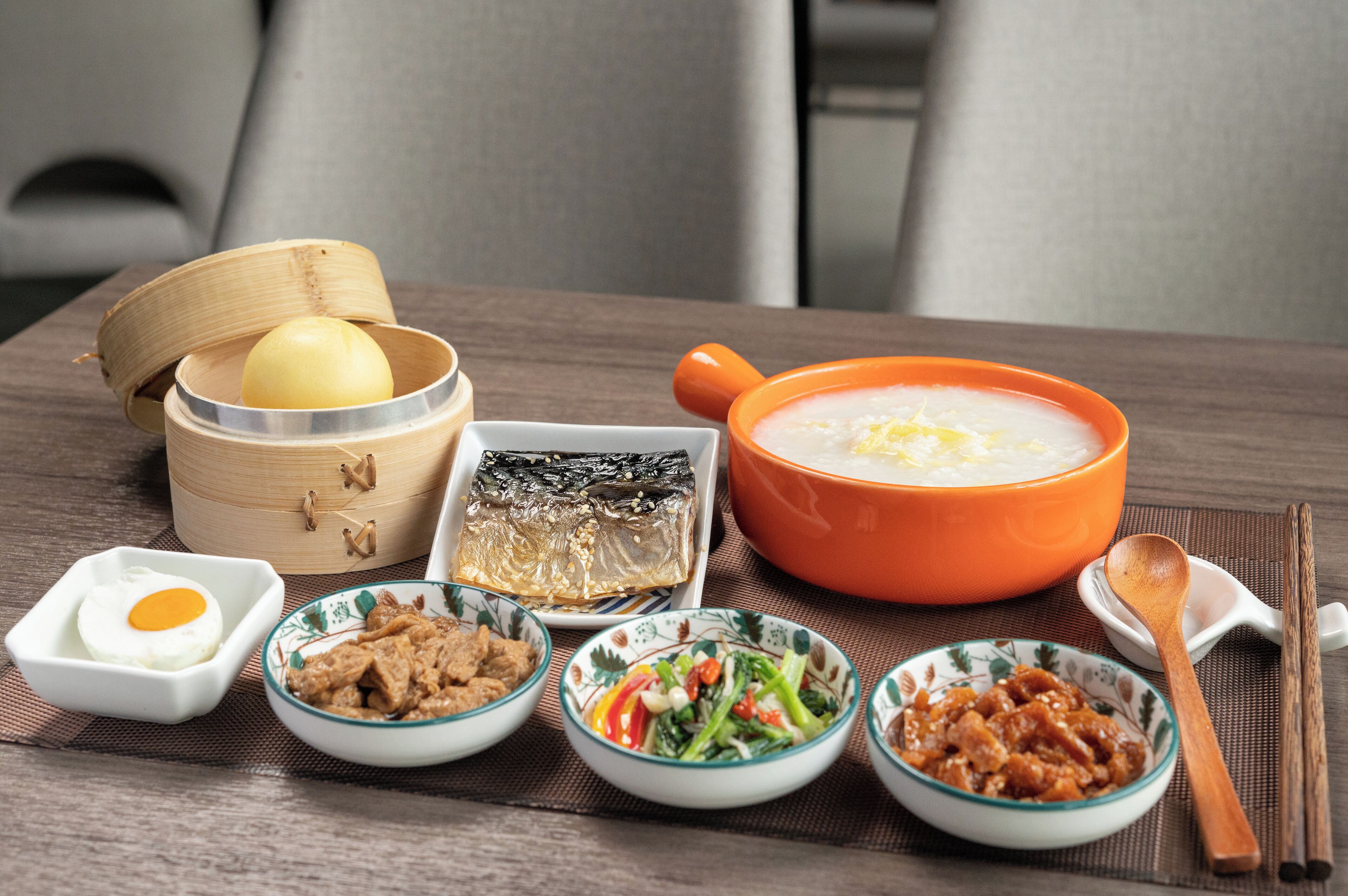 A table with various dishes including a bowl of soup, a steamed fish, and several side dishes.