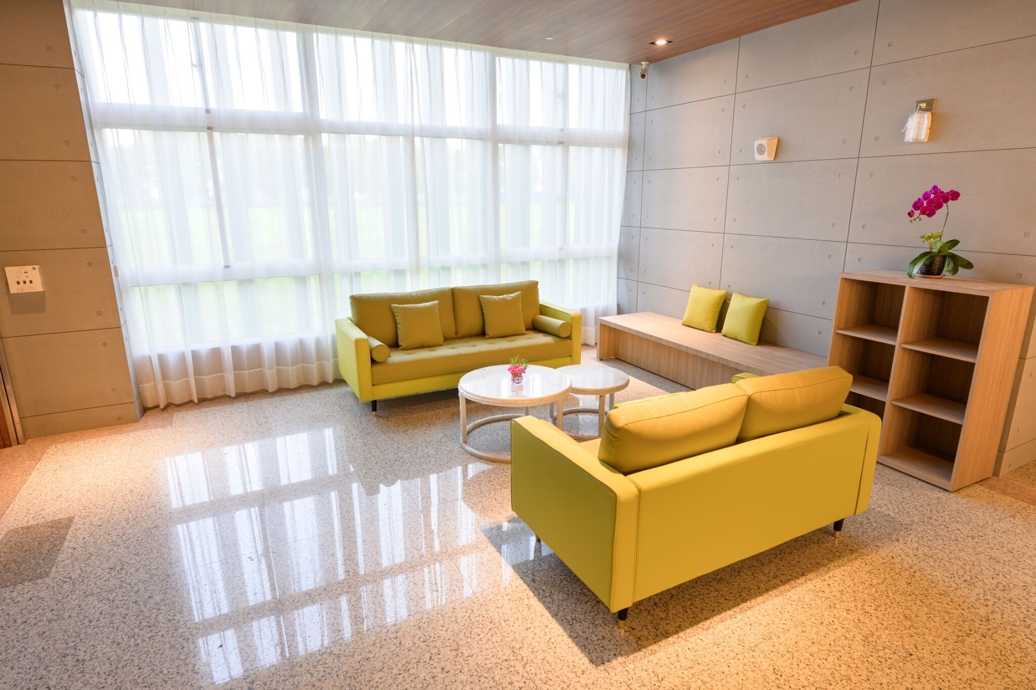A modern living room with yellow sofas, a coffee table, and a wooden bookshelf.