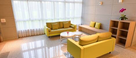 A modern living room with yellow sofas, a coffee table, and a wooden bookshelf.