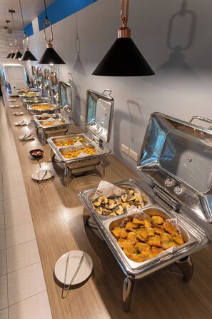 A buffet line with various food items, including salads, meats, and desserts, in a well-lit room with a blue accent wall. - TH Hotel (Changzhi)