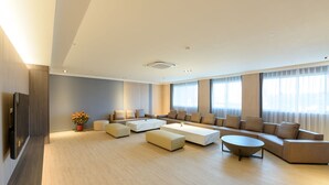Un salon spacieux avec un grand canapé d’angle, une table basse et un téléviseur posé sur un meuble en bois.