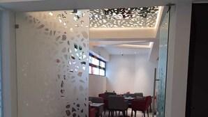 A modern interior with a dining area featuring a glass partition with a geometric pattern, a polished marble floor, and a ceiling with recessed lighting. - Amarterra Hotel Boutique (Mexico City)