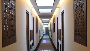 A hotel hallway with patterned wall panels, recessed lighting, and a carpeted floor. - Amarterra Hotel Boutique (Mexico City)