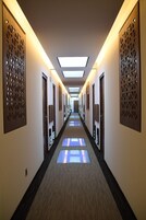 Un pasillo de hotel con paneles de pared estampados, iluminación empotrada y piso alfombrado.