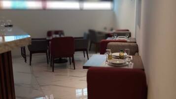 Un comedor moderno con una mesa larga y sillas, una pequeña barra y vistas al exterior a través de un ventanal.