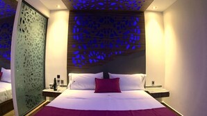 A modern hotel room with a large bed, a decorative ceiling, and a nightstand with a lamp. - Amarterra Hotel Boutique (Mexico City)