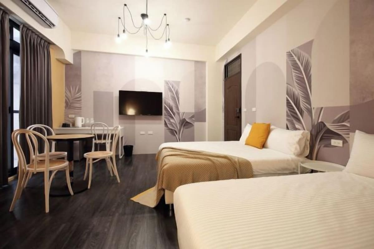 Een hotelkamer met een bed, een bureau met stoelen, een televisie en een kroonluchter.