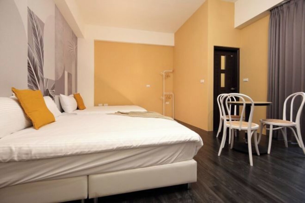 A hotel room with a large bed, a small table with chairs, and a door.