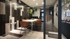 A modern dining area with a white table and brown chairs, a patterned wall, and a staircase leading to another level. - Light Year (Ji'an)
