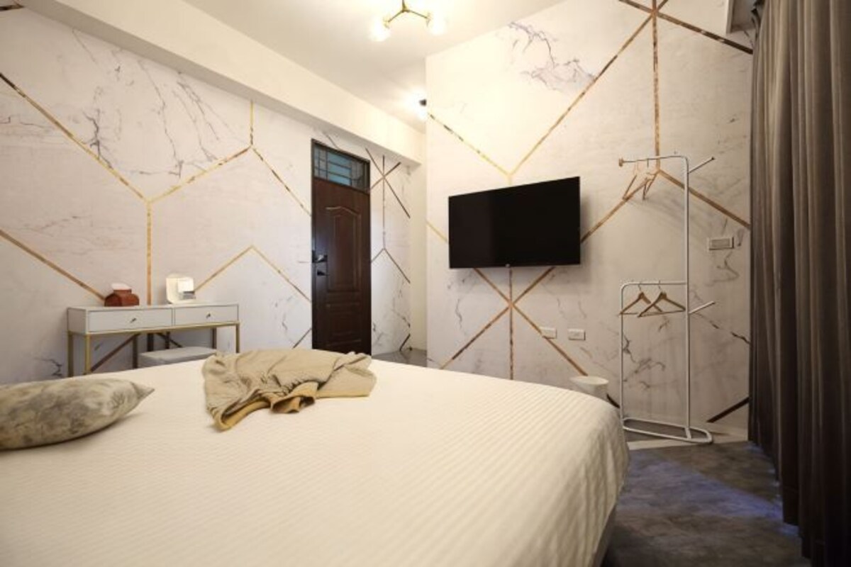 A bedroom with a bed, a desk, a TV, and a wardrobe.