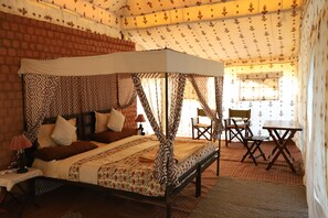 A four-poster bed with a canopy, a brick wall, a patterned ceiling, and a small table with chairs. - Hanuwantiya Tent City Jal Mahotsav (Harsud)