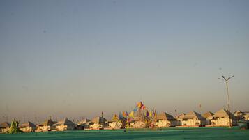 A row of white tents with a row of colorful flags in front.