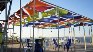 Un espace extérieur abrité, doté de tables et de chaises, offrant une vue sur une étendue d’eau.