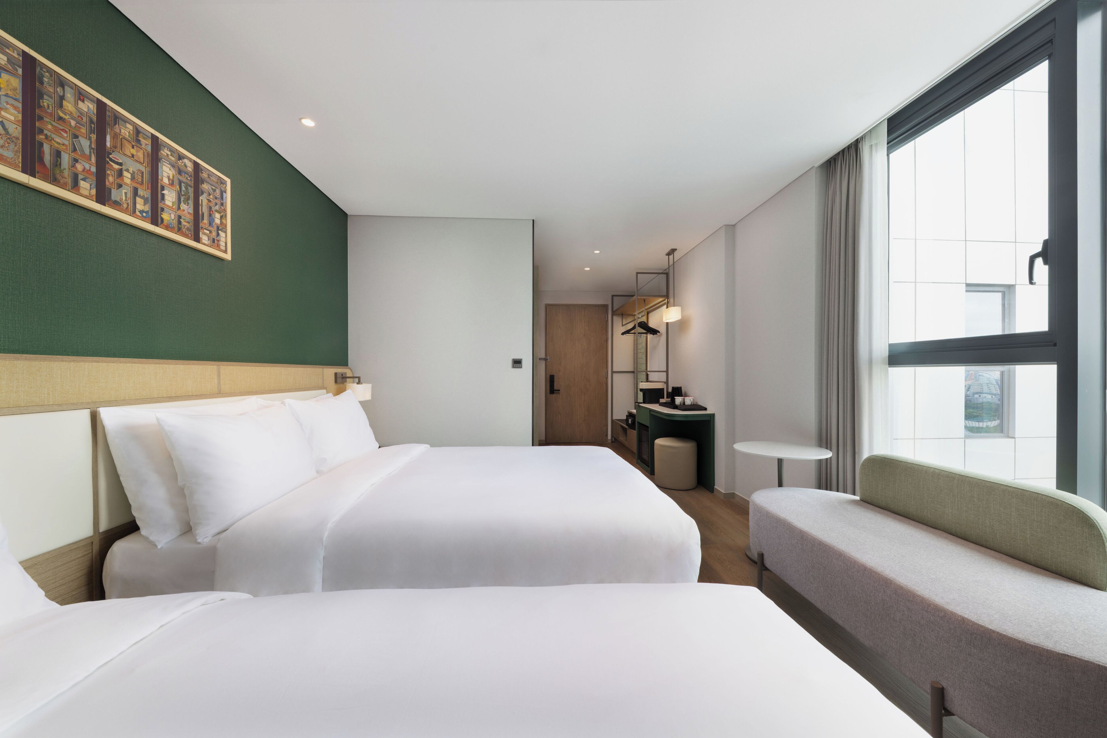 Habitación de hotel con dos camas, un área de descanso, una mesita, un espejo y una ventana.