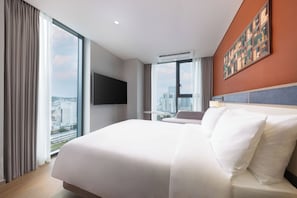 A hotel room with a large bed, a flat-screen TV mounted on the wall, and a city view through the windows. - Mercure Ambassador Seoul Dongdaemun (Seoul)