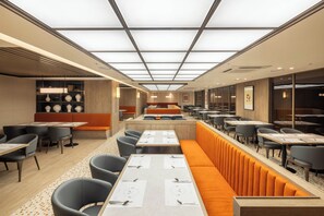 A modern restaurant with high ceilings, recessed lighting, and a mix of booth and table seating. - Mercure Ambassador Seoul Dongdaemun (Seoul)