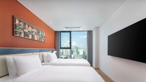 A hotel room with two beds, a large window with a city view, a mounted TV, and a colorful artwork on the wall.