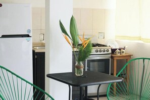Una cucina con frigorifero, fornello e un piccolo tavolo con un vaso di fiori.