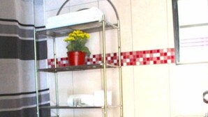 A bathroom with a toilet, a shower, a towel rack, and a sink.