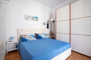 Un dormitorio con cama, mesitas de noche, lámpara y estante en la pared.