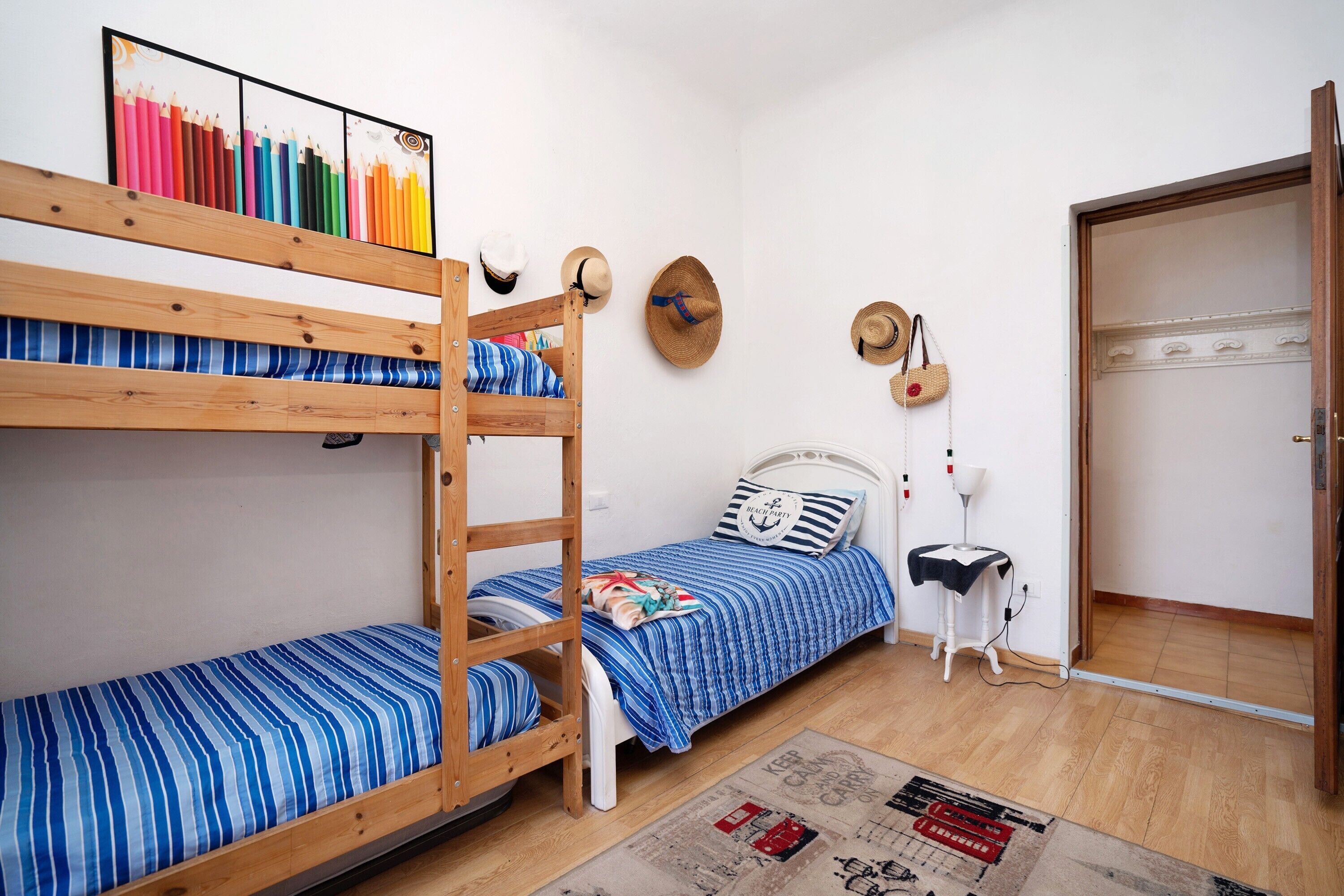 Una stanza con letti a castello, un comodino con una lampada e un appendiabiti a parete.