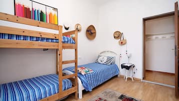 Una stanza con letti a castello, un comodino con una lampada e un appendiabiti a parete.
