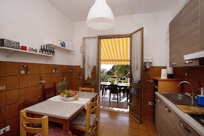 A kitchen with a dining table, chairs, a sink, and a window with a striped awning.