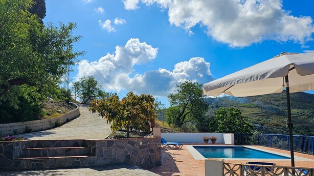 A pool area with a stone pathway, a small tree, and a view of hills in the background. - Holiday Home "Cortijo Airen" with Pool, Mountain View & Wi-Fi (Cómpeta)