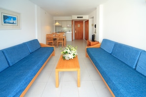 A living room with two blue sofas, a wooden coffee table, and a dining area with a wooden table and chairs.