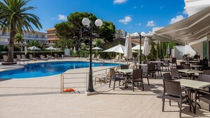 A poolside area with lounge chairs, umbrellas, and tables.