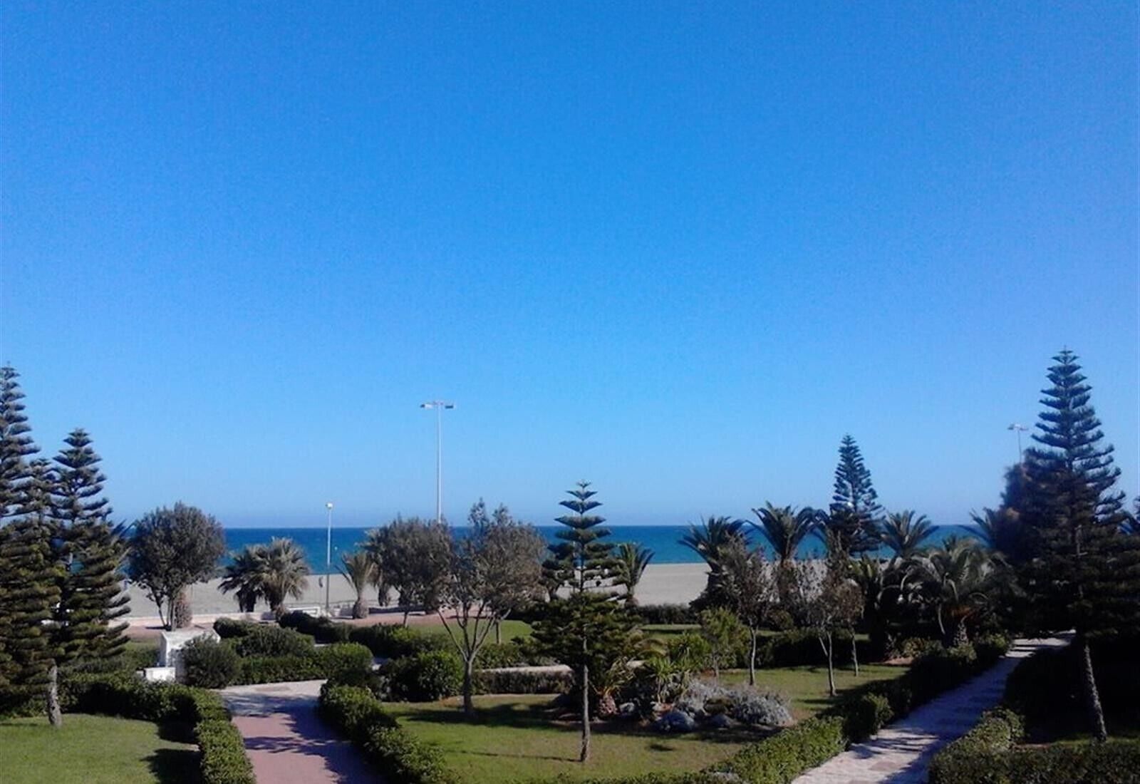 A landscaped area with pathways, trees, and a view of the sea.