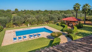 Uma piscina com espreguiçadeiras, um gazebo e vista para a paisagem ao redor.