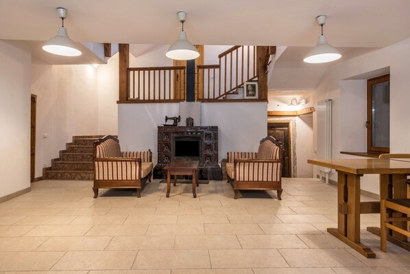 A spacious living area with a fireplace, wooden furniture, and a staircase.