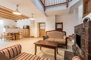 A spacious living area with a wooden table, striped sofa, and a fireplace.