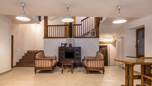 Amplia sala de estar con chimenea, muebles de madera y una escalera.