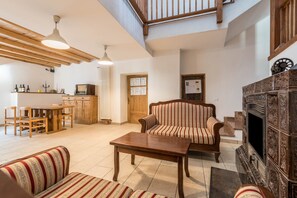 A spacious living area with a wooden table, striped sofa, and a fireplace.