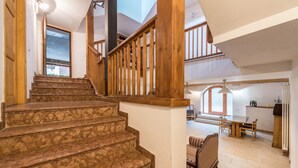 Una escalera con barandas de madera que lleva a un comedor con una mesa y sillas.