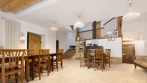 A spacious dining area with wooden furniture, a staircase, and a kitchen area. - Agriturismo "Al Gallo Nero Giallo" near Lake Garda with Mountain View & Terrace (Tenno)