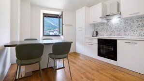 A modern kitchen with white cabinets, a wooden countertop, and a window with a mountain view. - Agriturismo "Al Gallo Nero Giallo" near Lake Garda with Mountain View & Terrace (Tenno)