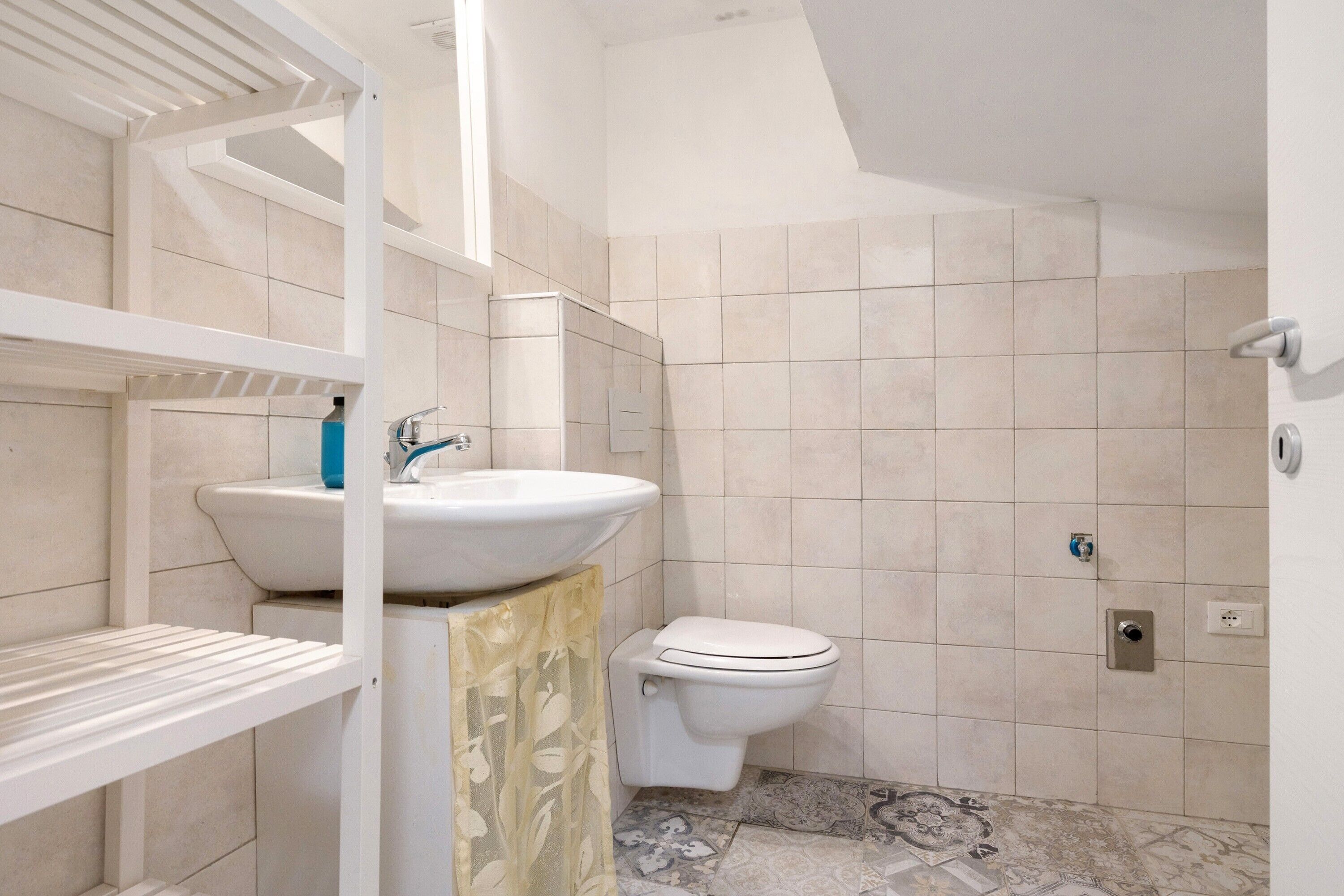 Ein Badezimmer mit Toilette, Waschbecken und Fliesenwänden.