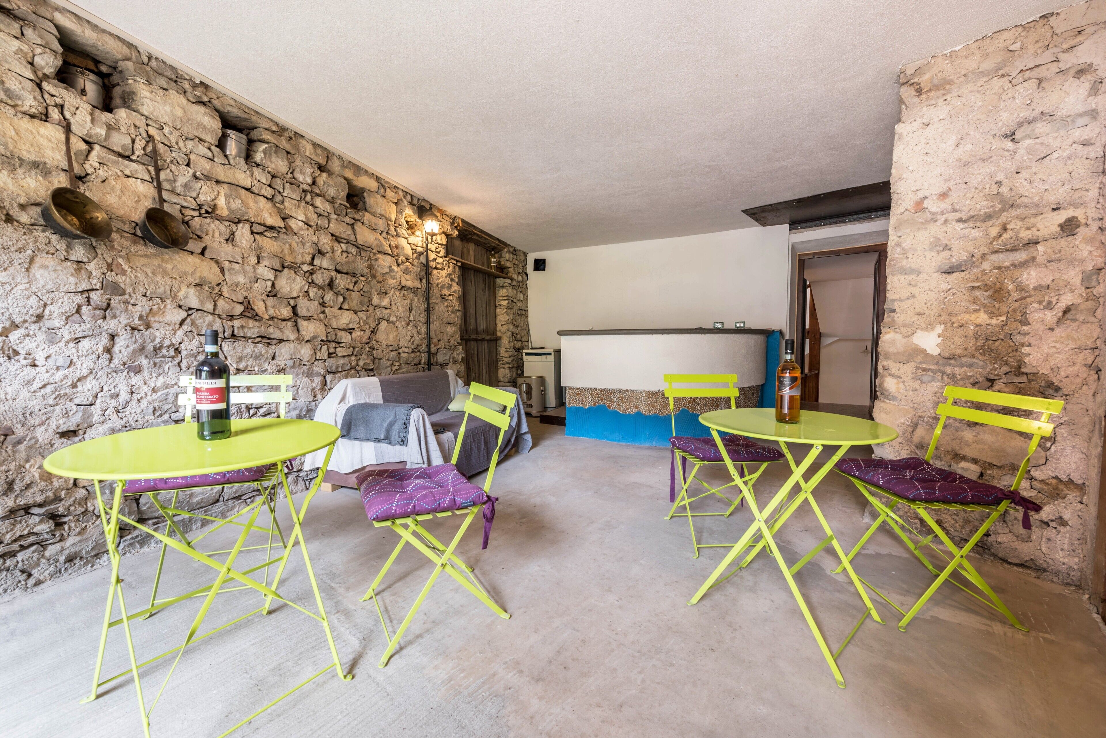 Una habitación rústica con paredes de piedra, un banco de piedra y una mesa con sillas.