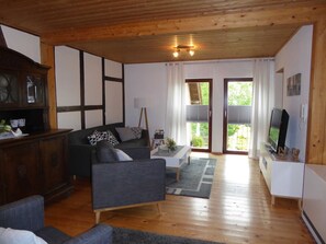 Uma sala de estar acolhedora com teto de madeira, um sofá, uma mesa de centro e uma televisão.