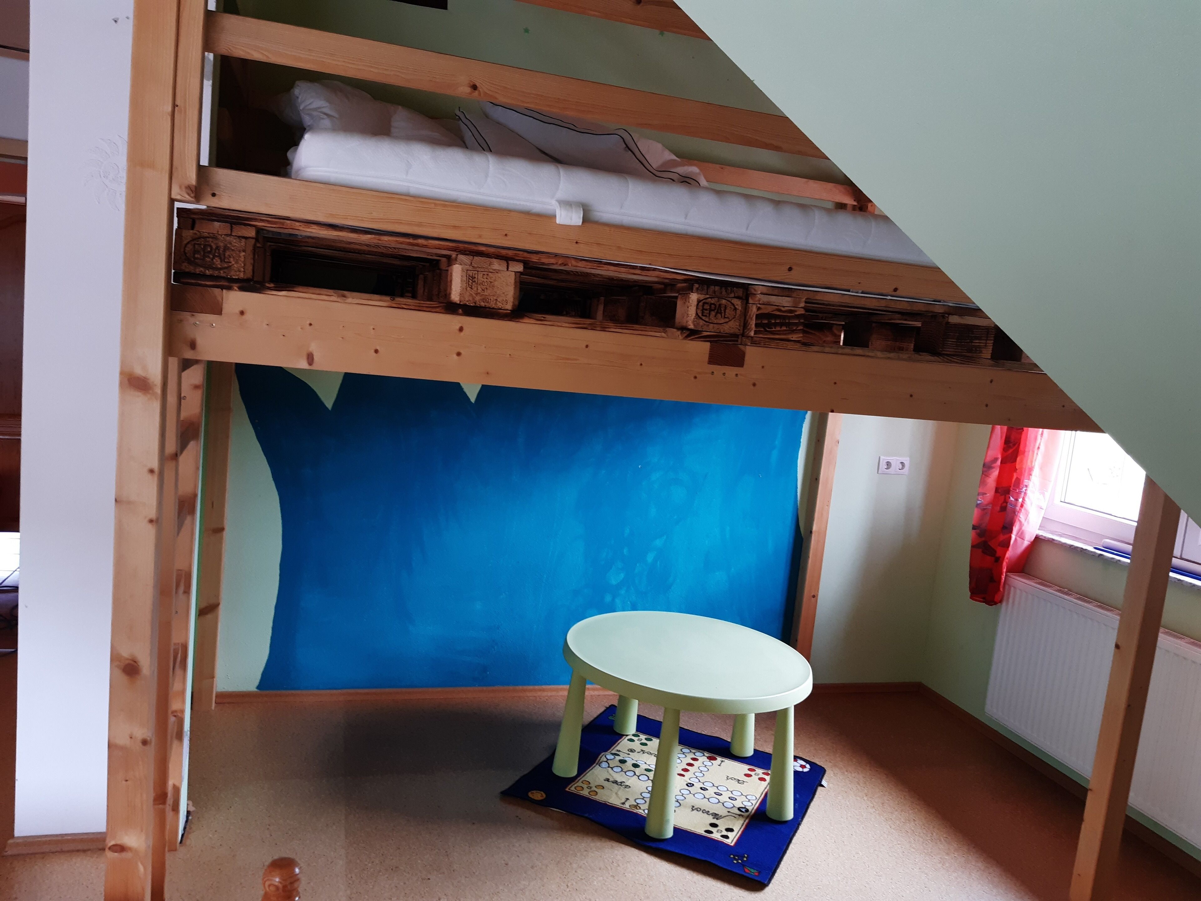 Ein Zimmer mit einem Etagenbett, einem kleinen Tisch und einer blauen Wand.