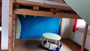 Quarto com uma cama beliche, uma mesinha e parede azul.