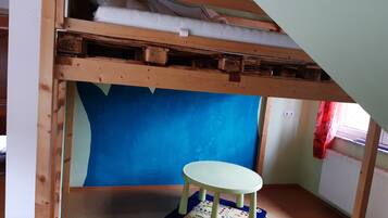 Ein Zimmer mit einem Etagenbett, einem kleinen Tisch und einer blauen Wand.