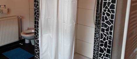 Un baño con cabina de ducha, inodoro y radiador.