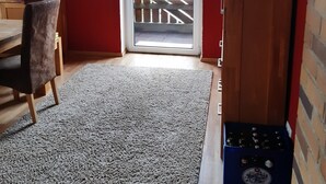 Quarto com teto de madeira, parede vermelha, escrivaninha de madeira, cadeira, tapete branco, armário de madeira e porta de vidro deslizante que dá para uma área externa.